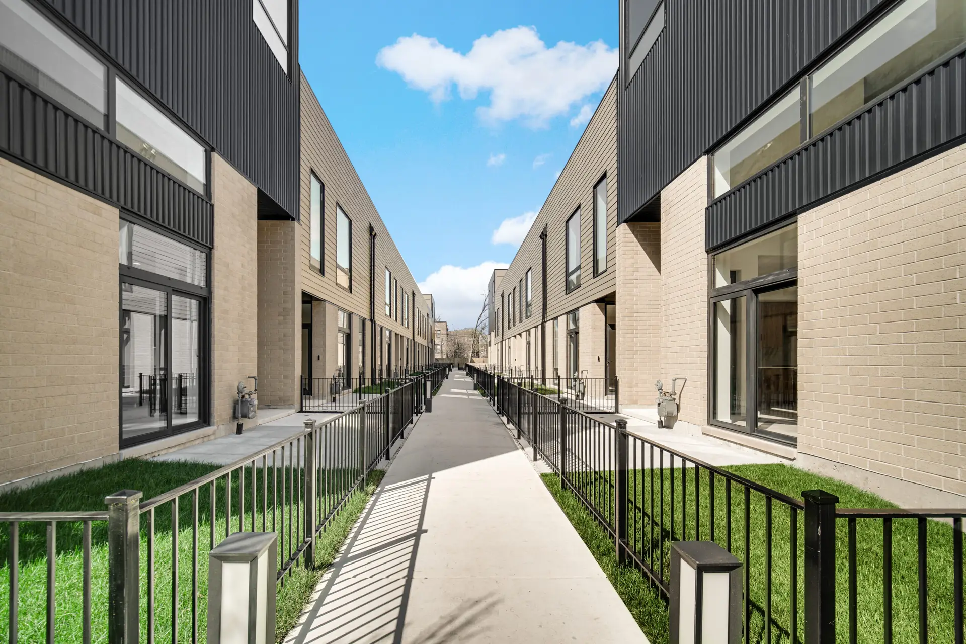 Exterior Walkway down the center of the townhome community, with the front entrances of units on either side facing the walkway.